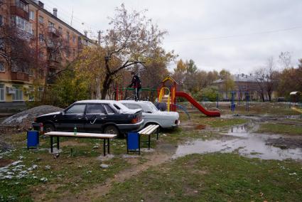 мальчики играют у старой машины Волга, на детской площадке во дворе жилого дома