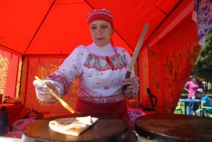 девушка в традиционном русском наряде печет блины