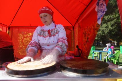 девушка в традиционном русском наряде печет блины
