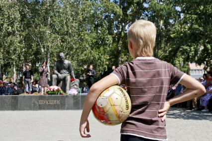 Мальчик с футбольным мячом напротив памятника режиссеру, актеру и писателю Василию Шукшину.