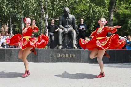 Две девушки танцуют перед памятником режиссеру, актеру и писателю Василию Шукшину.