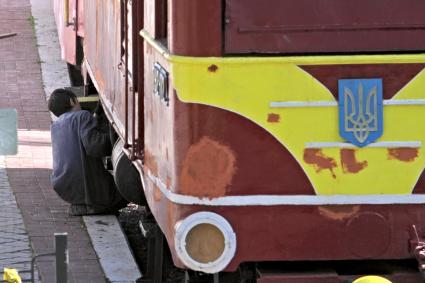 Мужчина чинит подвижной украинский железнодорожный состав.