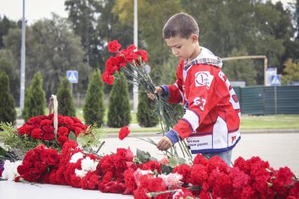 Ребенок с цветами у мемориала погибшим хоккеистам.