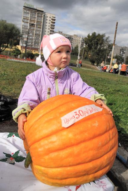 Девочка на улице с большой тыквой.