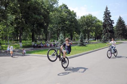 Дети катаются на велосипеде в парке.