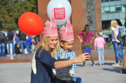 Празднование Дня города на Цветном бульваре. На снимке: женщина с ребенком фотографируются на телефон.