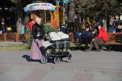 Женщина с детской коляской во время прогулки.