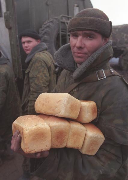 Вторая чеченская война. Урус-Мартан. Российский солдат держит в рках буханки хлеба.