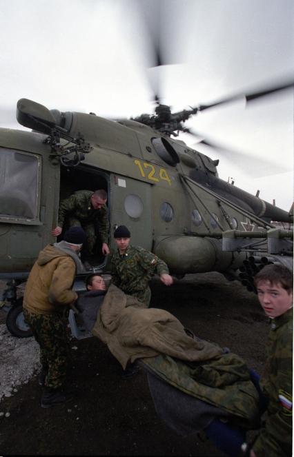 Вторая чеченская война. Урус-Мартан. Российские военнослужащие заносят на борт вертолета Ми-8 раненого бойца.