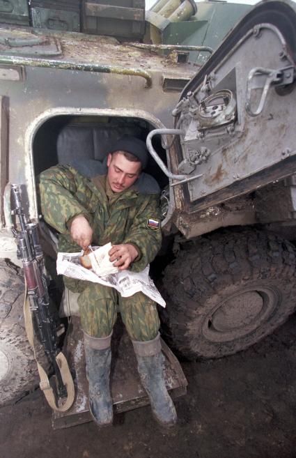 Вторая чеченская война. Ханкала. База российских войск. На снимке: российский военнослужащий режет сало и хлеб на газете `Комсомольская правда`.