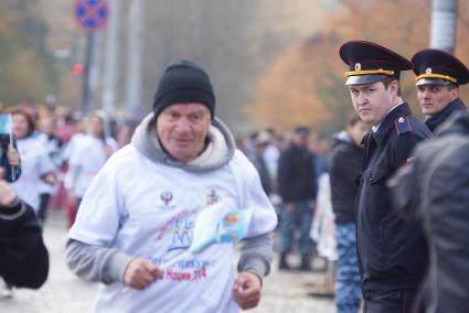 Сотрудник полиции пристально смотрит в спину бегунам на забеге \"Кросс нации 2014\" в Екатеринбурге