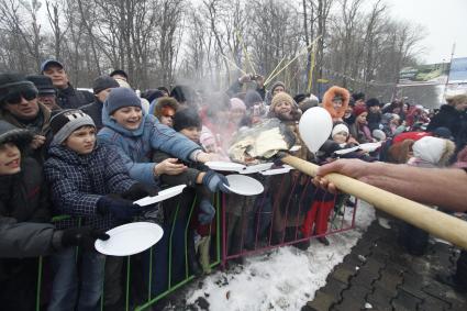 Празднование масленицы. Повора раздают блины с лопат.