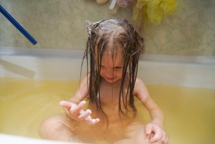 ребенок купается в ванной, в желтоватой воде