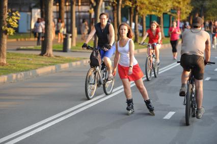 Парк Горького. На снимке: женщина на велосипеде и девушка на роликовых коньках.