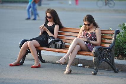 Парк Горького. На снимке: девушки сидят на лавочке и смотрят в телефон.