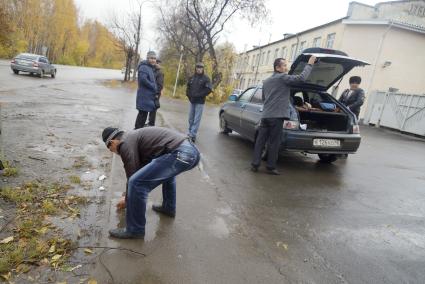 Мусульманин моет руки в луже после погрузки жертвенного барана в багажник машины, в день праздника жертвоприношения Курбан-байрам у Медной мечети имени имама Исмаила аль-Бухари в городе Верхняя Пышма