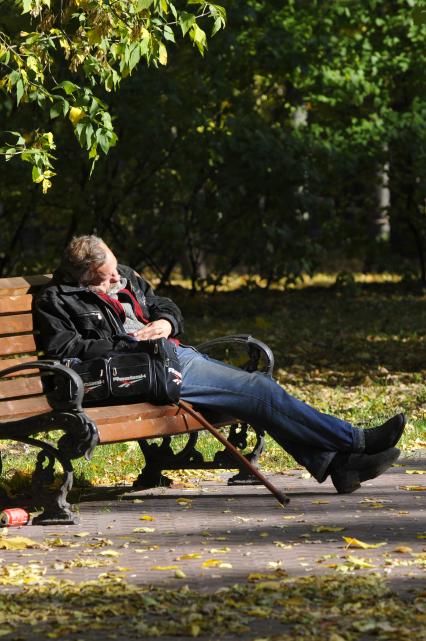Мужчина спит на скамейке в парке.