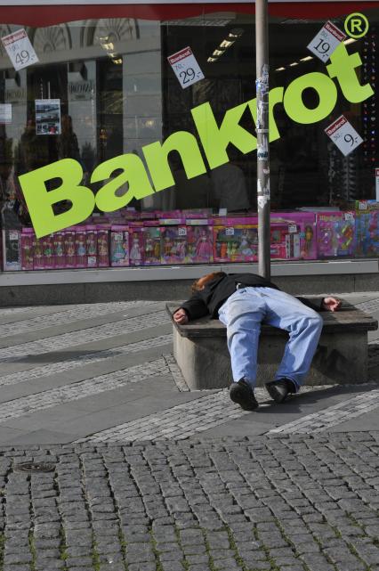 Прага. На снимке: пьяный мужчина спит на фоне витрины с надпистю Bankrot.