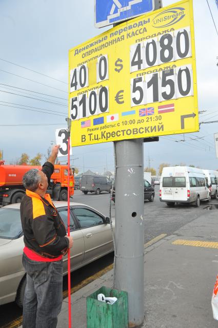 Мужчина меняет курс валюты на табло около метро `Рижская`.