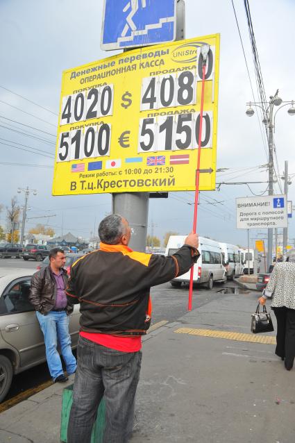 Мужчина меняет курс валюты на табло около метро `Рижская`.