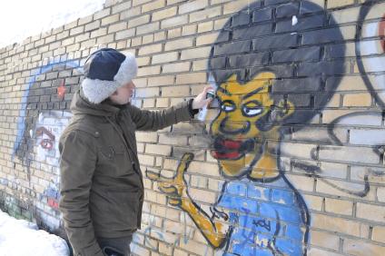 Мужчина рисует граффити на стене.
