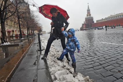 Первый снег в Москве. На снимке: женщина с ребенком перешагивают через снег на Красной Площади.