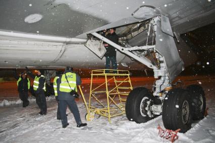 Работник таможенной службы осматривает отсек для шасси самолета.