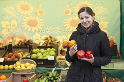 Девушка держит болгарские перцы на рынке.