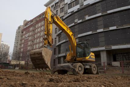 Экскаватор разравнивает площадку для строительства.