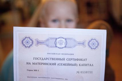 Сертификат на материнский капитал на фоне ребенка.