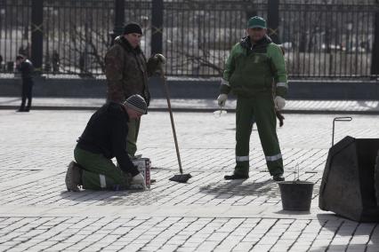 Рабочие чинят брусчатку