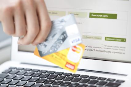Человек совершает покупку через интернет используя кредитную карту