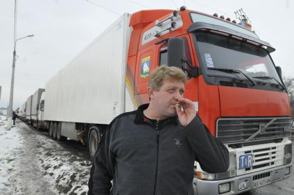 Фуры стоят в пробке в сторону аэропорта Домодедово на Каширском шоссе. На снимке: водитель курит у машины.
