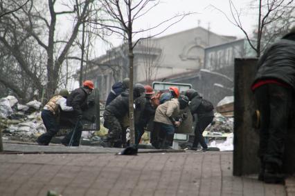 Беспорядки в Киеве. Представители оппозиции, закрываясь щитами, передвигаются по улице.