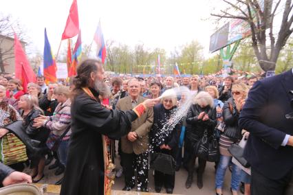 Ситуация в Луганске. На снимке: батюшка окропляет святой водой местных жителей во время Крестного хода. Люди направляются к зданию Службы безопасности Украины (СБУ) на митинг, где по завершению состоится народное голосование.