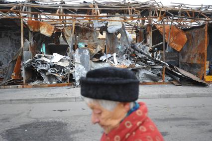 Донецк. Рынок рядом с железнодорожным вокзалом. На снимке: женщина идет на фоне сгоревших павильонов.