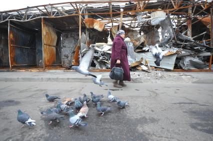 Донецк. Рынок рядом с железнодорожным вокзалом. На снимке: женщина идет на фоне сгоревших павильонов.
