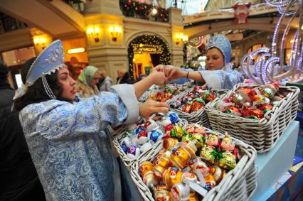 Ярмарка елочных игрушек в ГУМе. На снимке: девушки в костюме Снегурочки  и елочные шары.