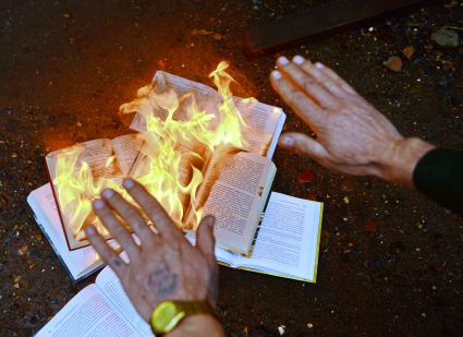 Человек греет руки над горящей книгой