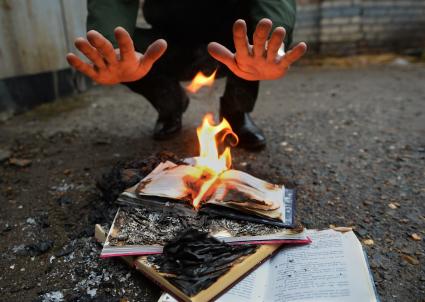Человек греет руки над горящей книгой