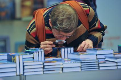 16-я Международная ярмарка интеллектуальной литературы Non/fiction в Центральном Доме Художника. На снимке: мужчина рассматривает книгу через увеличительное стекло.