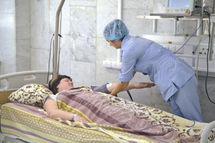 Медсестра подключает женщину к приборам в палате реанимации роддома БСМП №10