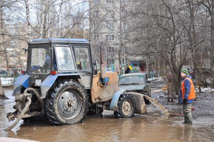 Трактор откачивает воду из затопленного из-за аварии двора