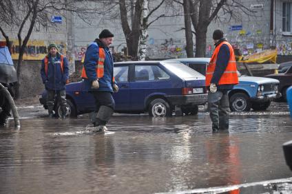 Сотрудники водоканала на затопленной из-за аварии дороге во дворе жилого дома