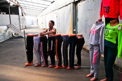Вьетнамец стоит у манекенов со спортивной одеждой на рынке во время рейда УФМС по поиску нелегальных мигрантов