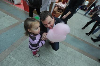 Гастрономический фестиваль `Фуд Шоу` в Гостином Дворе. На снимке: девочка и мужчина едят сахарную вату.