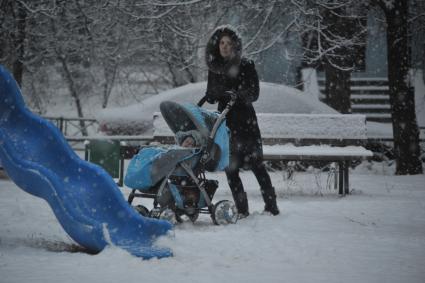 Снегопад в Москве. На снимке:  женщина с ребенком в коляске.