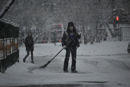 Снегопад в Москве. На снимке:  мужчина подметает тротуар от снега