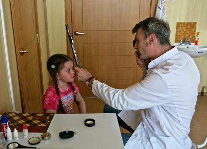 Прием врача. Врач проверяет зрение у ребенка.