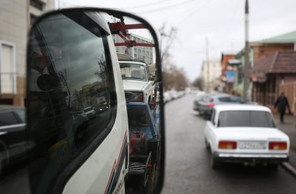 Вид в зеркале эвакуатора, который отвозит машину на штраф стоянку за неправильную парковку.